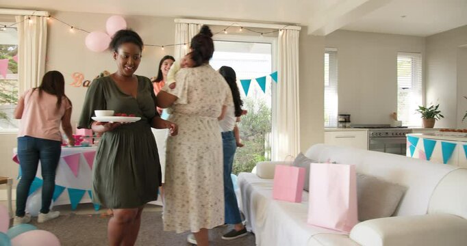 Group of happy multiracial, white and black female friends with babies cleaning and talking at a bab