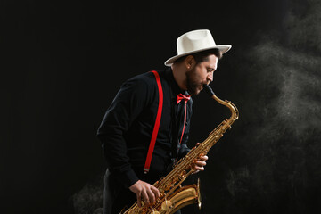 Professional musician playing saxophone on black background with smoke