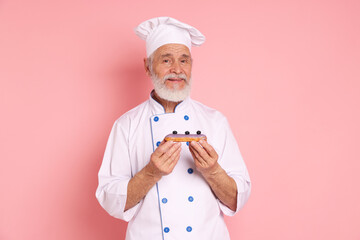 Professional pastry chef with delicious eclair on pink background