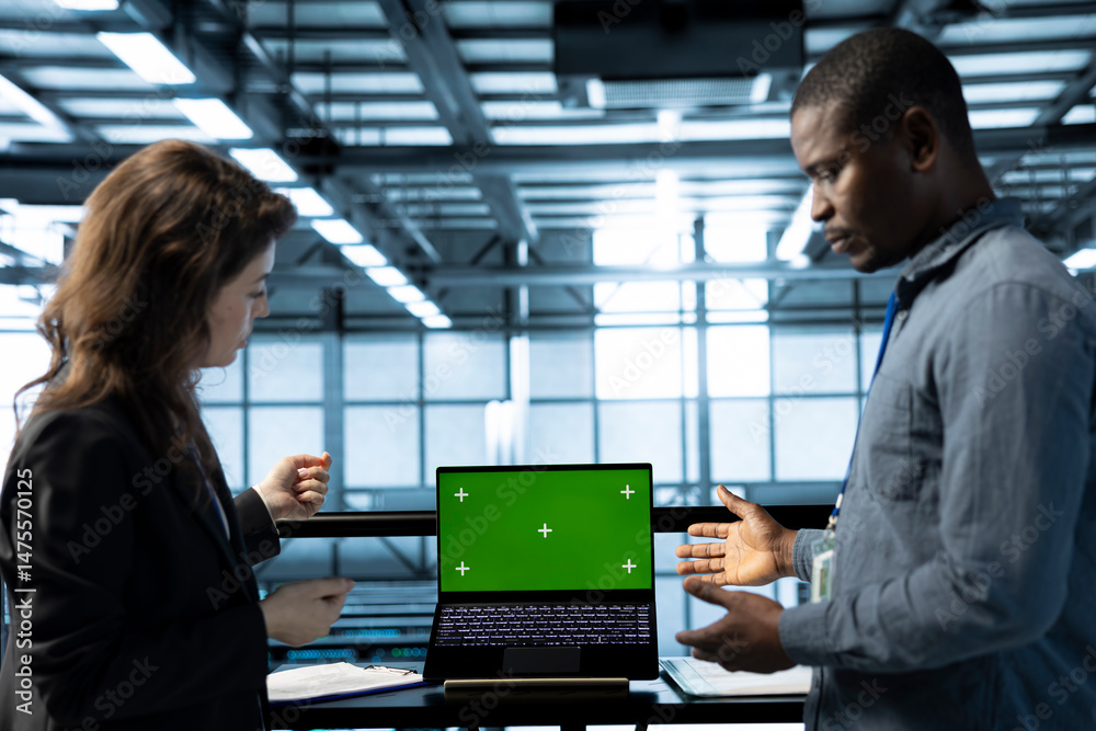 Poster engineers in data center using isolated screen mockup laptop, inspecting server clusters, updating n