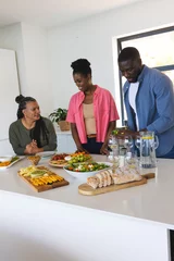 Selbstklebende Fototapeten African American family preparing and enjoying meal together in modern kitchen © WavebreakMediaMicro