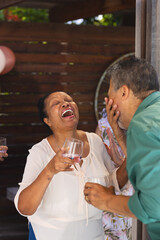 Seniors laughing while drinking at lively outdoor celebration with friends