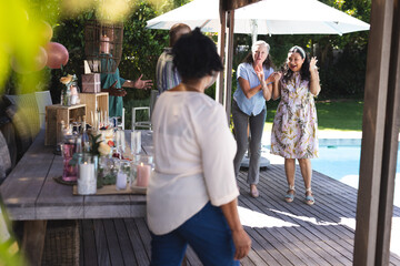 Seniors celebrating outdoors, clapping and smiling near pool at garden party