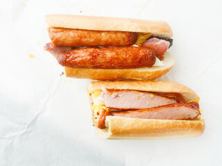 Traditional tasty Irish breakfast roll with white bread, sausage, bacon or rasher, fried egg and black pudding on greasy wrapping paper. Popular high calorie meal in Ireland. Classic dish