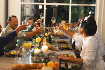 Seniors toasting with wine glasses at elegant dinner party, celebrating together