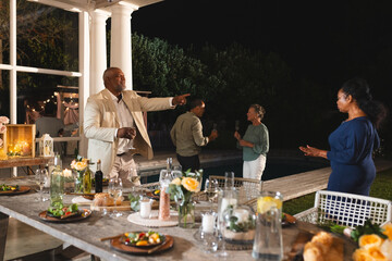 Celebrating at outdoor dinner party, senior friends sharing conversation and laughter