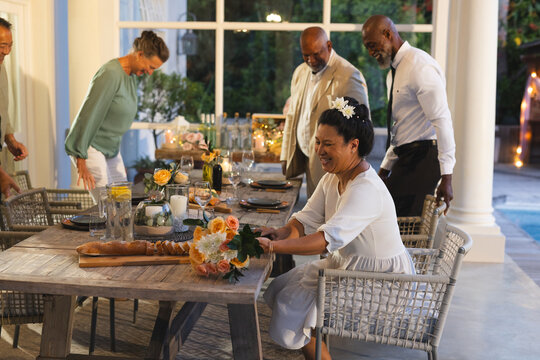 Gathering around outdoor dining table, seniors laughing during festive celebration