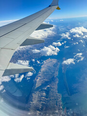 Obraz premium AERIAL: Window seat view on a flight over the dramatic coastline of Croatia. Flying over Adriatic Sea and rolling clouds reveals rugged islands surrounded by blue water. Scenic views during air travel