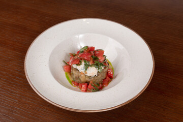 Salad with eggplant, feta cream, tomatoes on a plate on a table in a restaurant