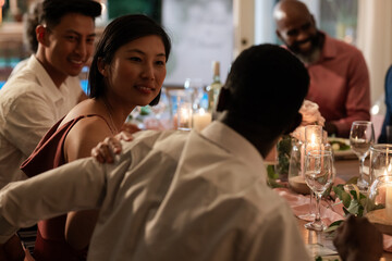 Guests enjoying lively conversation at elegant wedding dinner table with candles