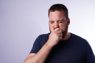 Young guy with ginger beard coughing in his hand.