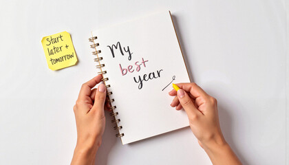 Hands writing "My best year" in a notebook with sticky note