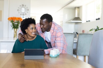 Couple enjoying morning coffee and conversation at home with tablet on table