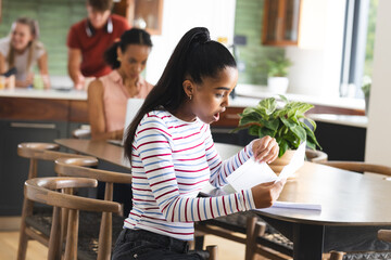 Teen girl reading letter at home, looking surprised and excited