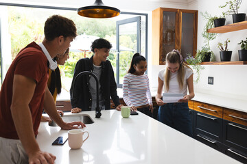 Teen friends in kitchen reading letter, sharing excitement and smiling together
