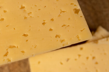 cheese with holes for cooking, pieces of sliced cheese on a board, close up