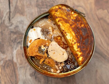 Open can of fermented surstromming fish on wooden table