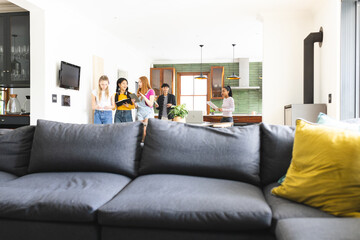 Teenagers in living room celebrating with friends, chatting and enjoying together
