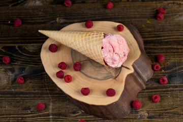 raspberry ice cream lies on a walnut board, ripe red raspberries and raspberry cold natural ice cream on the table, top view