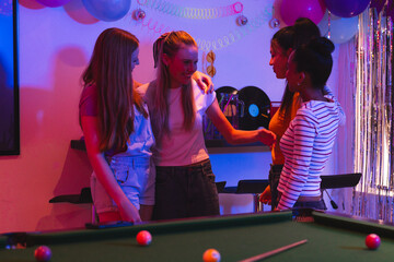 Fototapeta premium Teen girls celebrating together around pool table, enjoying festive party atmosphere