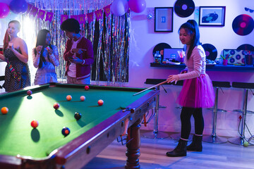 Fototapeta premium Teen playing pool at birthday party, friends enjoying music and snacks nearby