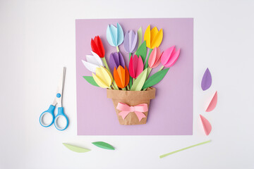Handmade paper flower bouquet in brown pot with pink bow on purple background, creative Mothers Day...