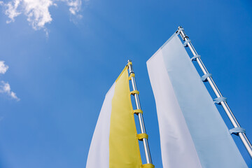 Vatican White and Yellow Flags Waving Against Blue Sky Background