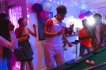 Teenagers celebrating at home, playing pool and dancing with colorful balloons © WavebreakMediaMicro