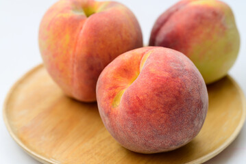 Peaches fruit on wooden plate with white background