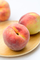 Peaches fruit on wooden plate with white background