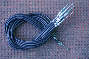 set of black gray motorcycle brake cables in a coil lie on a brown table