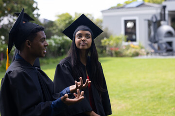 Graduating students in caps and gowns celebrating outdoors with joyful expressions