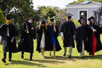 Graduating students in caps and gowns celebrating joyfully outdoors together