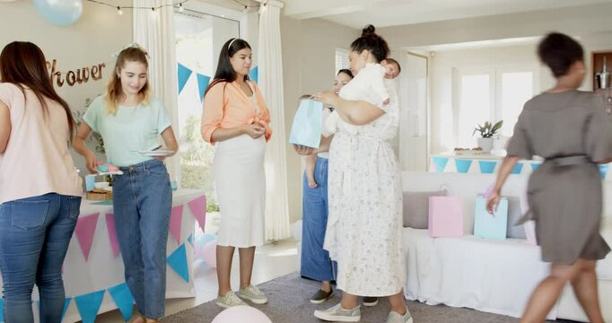 Group of happy multiracial, white and black female friends with babies cleaning and talking at a bab
