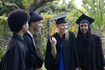 Graduating students in caps and gowns celebrating joyfully outdoors together