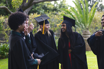 Graduating students in caps and gowns celebrating outdoors with joyful laughter