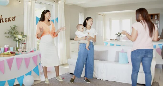 Group of happy multiracial, white and black female friends with babies cleaning and talking at a bab