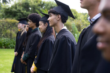 Graduating students in caps and gowns standing outdoors, smiling and celebrating