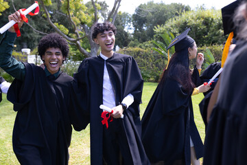 Celebrating outdoors, graduating students holding diplomas and smiling joyfully