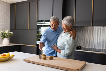Elderly couple in modern kitchen preparing meal together, sharing joyful moment