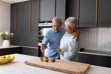 Selbstklebende Fototapeten Elderly couple in modern kitchen preparing meal together, sharing joyful moment © wavebreak3