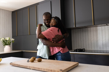 African American couple embracing in modern kitchen, expressing joy and affection