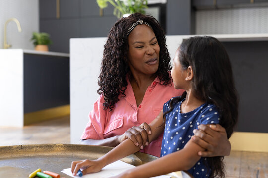 African American mother and daughter smiling while drawing together at home