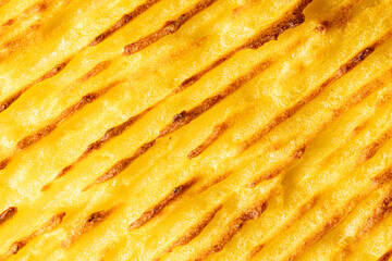 A background with the texture of mashed potatoes baked until golden brown in the oven. Close-up, macro photography. Use for menu and banner.
