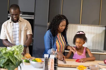 Selbstklebende Fototapeten Family cooking together in modern kitchen, smiling and preparing fresh vegetables © wavebreak3