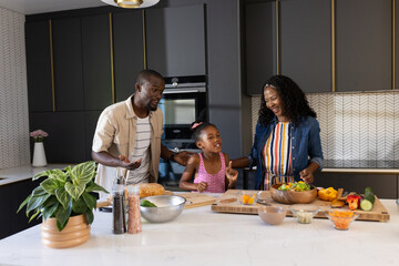 Family preparing healthy meal together in modern kitchen, sharing joyful moments