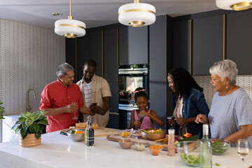 Cooking fresh salad, family in modern kitchen sharing laughter and bonding together