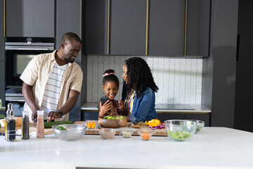 African American family cooking together in modern kitchen, sharing joyful moments