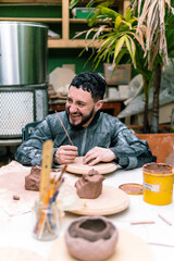Potter skillfully shaping clay on a pottery wheel in a vibrant workshop, using various tools while...