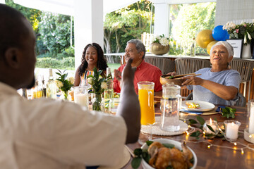 Family enjoying outdoor meal together, sharing laughter and stories at festive table